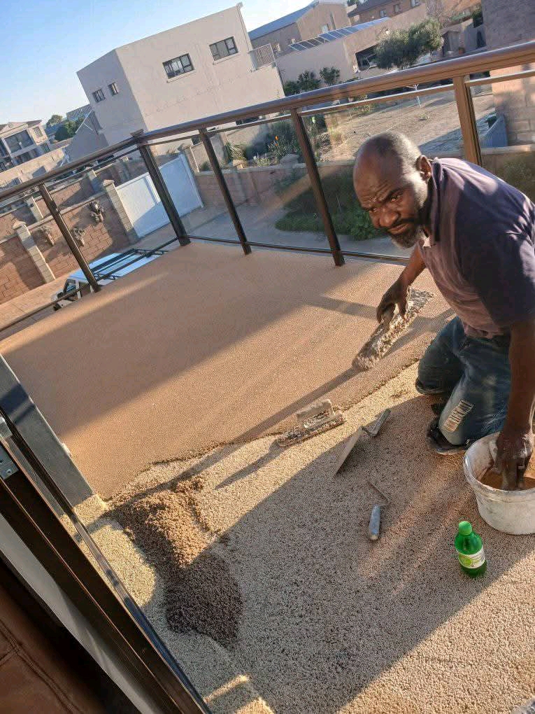 Installer spreading quartz carpet on balcony surface